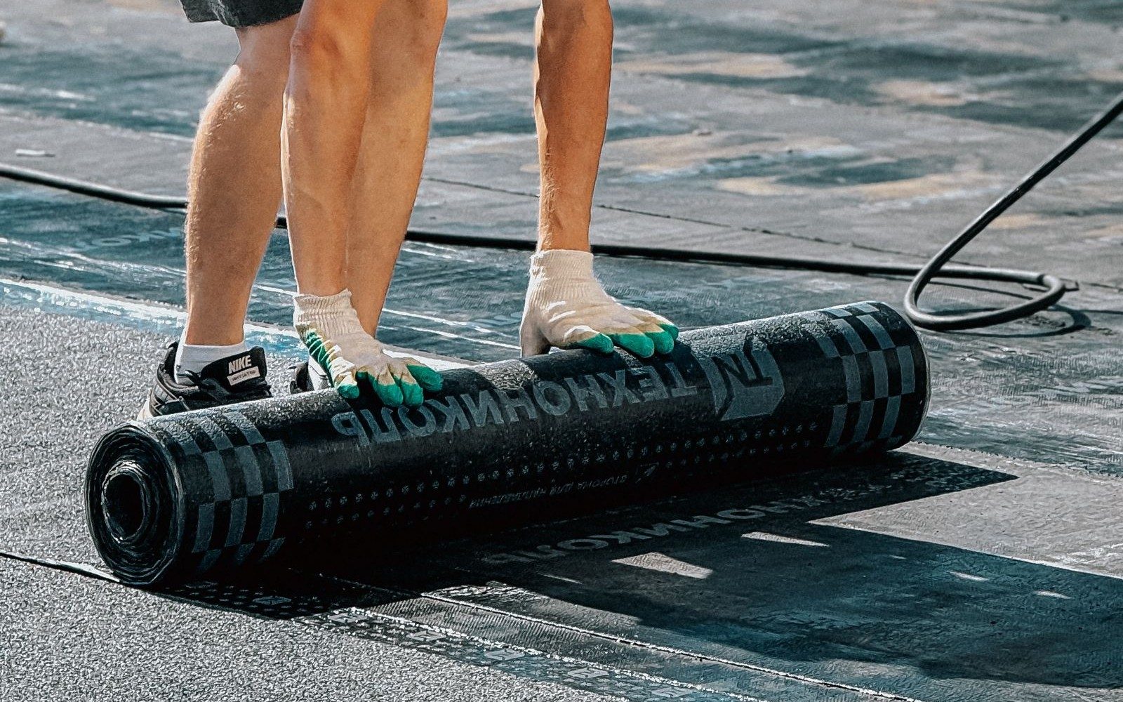 Roofer unrolling EPDM membrane on a flat roof